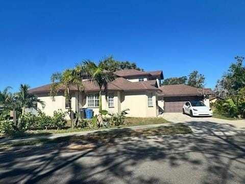 4015 Woodacre Ln, Tampa, FL 33624 - view of front of home with an attached garage, concrete driveway, and stucco siding