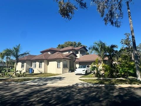 4015 Woodacre Ln, Tampa, FL 33624 - view of front facade with stucco siding, concrete driveway, and a garage