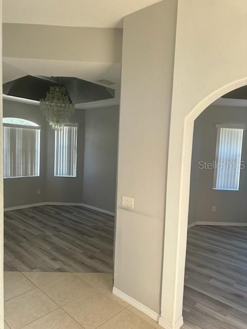 4015 Woodacre Ln, Tampa, FL 33624 - spare room featuring arched walkways, a chandelier, wood finished floors, baseboards, and healthy amount of natural light