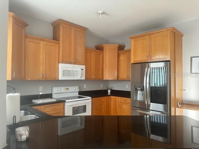 4015 Woodacre Ln, Tampa, FL 33624 - kitchen with white appliances, dark countertops, and a sink