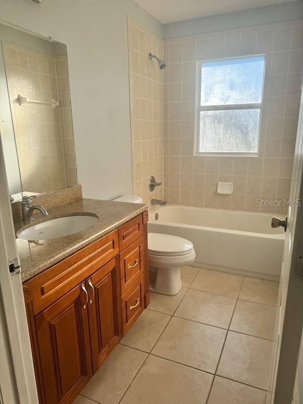 4015 Woodacre Ln, Tampa, FL 33624 - full bathroom with vanity, tile patterned floors,  shower combination, and toilet