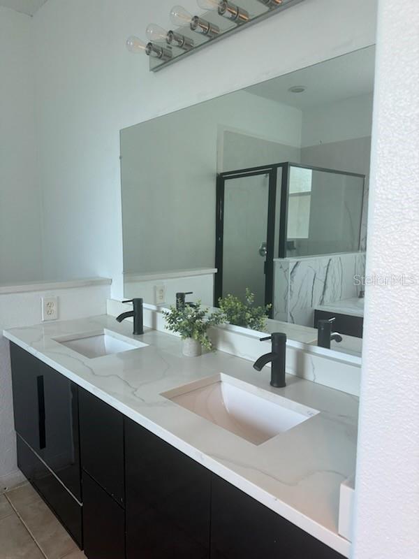 4015 Woodacre Ln, Tampa, FL 33624 - bathroom featuring a shower stall, double vanity, and tile patterned floors