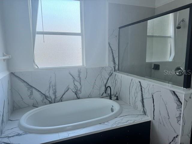4015 Woodacre Ln, Tampa, FL 33624 - bathroom with healthy amount of natural light, a tub with marble appearance, and a shower