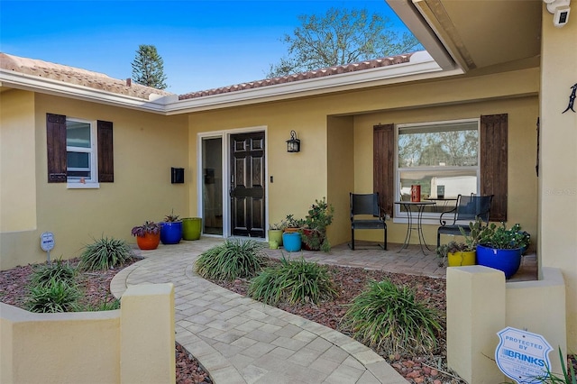 property entrance featuring a patio, a tiled roof, and stucco siding