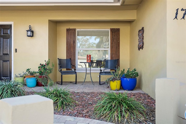 property entrance with covered porch and stucco siding