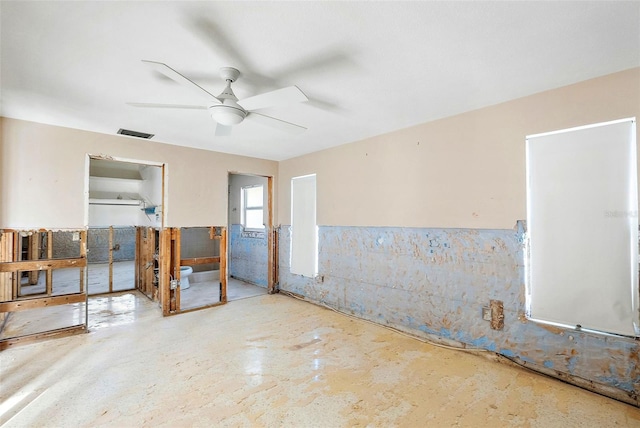 unfurnished room featuring a wainscoted wall, a ceiling fan, visible vents, and concrete flooring