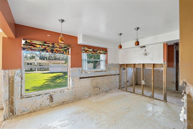 kitchen featuring hanging light fixtures, unfinished concrete flooring, and wainscoting