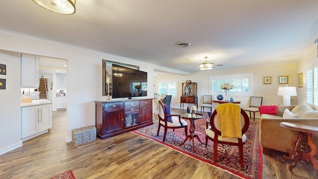 dining area with a healthy amount of sunlight, light wood-type flooring, and crown molding