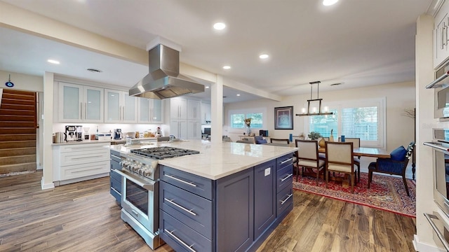 kitchen with high end range, white cabinets, hanging light fixtures, dark hardwood / wood-style floors, and range hood