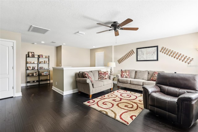 living room featuring ceiling fan, dark wood-type flooring, and a textured ceiling