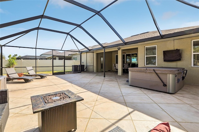 view of patio with central AC, a hot tub, a fire pit, and glass enclosure