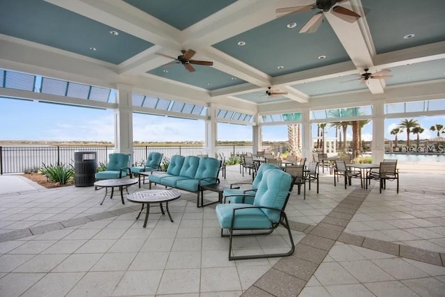 sunroom with plenty of natural light, a water view, and coffered ceiling