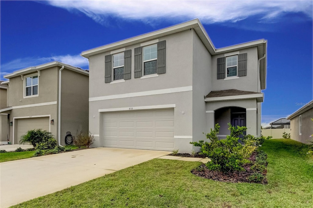 view of property with a garage and a front lawn