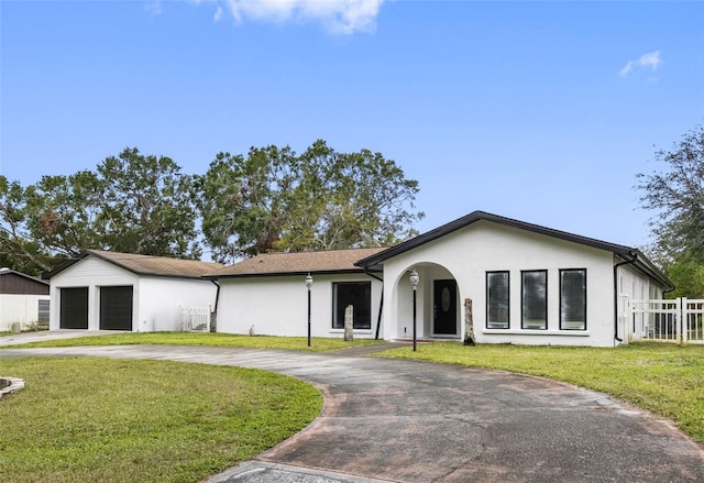 ranch-style home with a garage, an outbuilding, and a front lawn