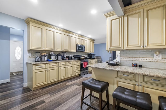 kitchen with backsplash, dark hardwood / wood-style flooring, stainless steel appliances, and cream cabinetry