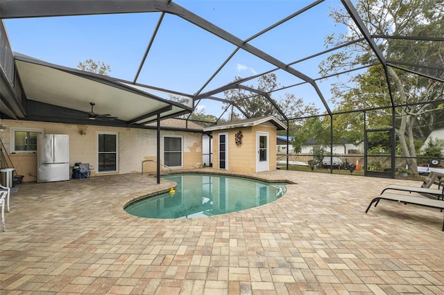 view of swimming pool with glass enclosure, ceiling fan, and a patio