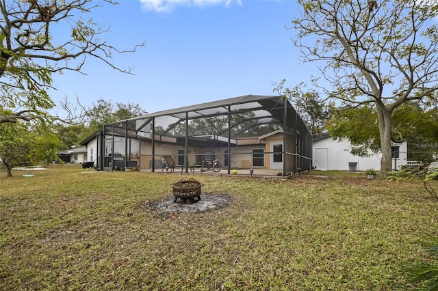 back of house featuring a lanai, a lawn, and an outdoor fire pit