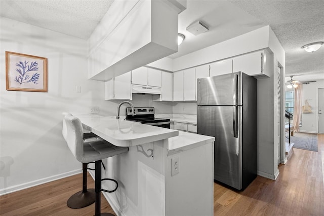 kitchen featuring stainless steel appliances, a kitchen breakfast bar, premium range hood, kitchen peninsula, and white cabinets