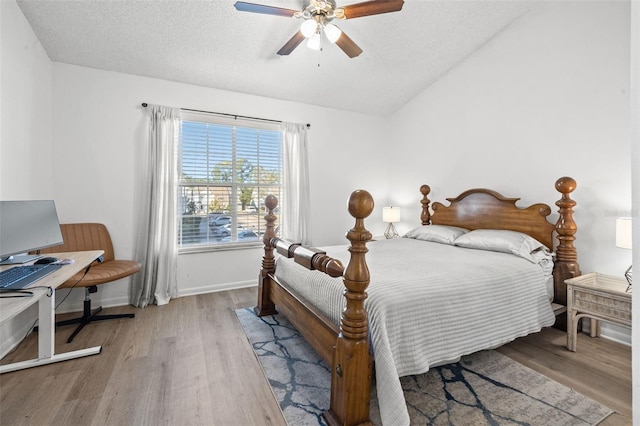 bedroom with a textured ceiling, light hardwood / wood-style floors, ceiling fan, and lofted ceiling