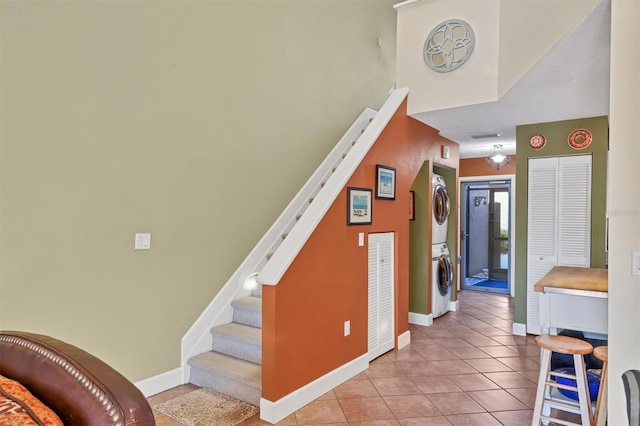 stairs featuring tile patterned flooring and stacked washer and clothes dryer