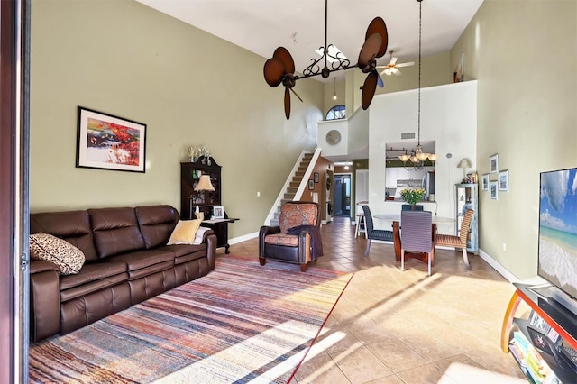 living room featuring tile patterned floors, a towering ceiling, and ceiling fan with notable chandelier