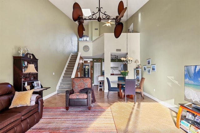 tiled living room featuring ceiling fan with notable chandelier and a high ceiling