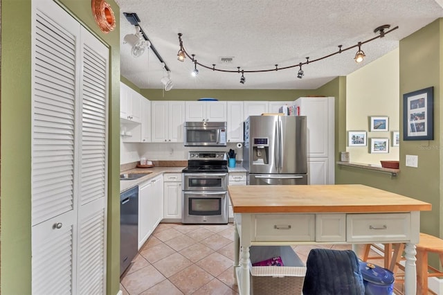 kitchen featuring white cabinets, a textured ceiling, stainless steel appliances, and light tile patterned flooring