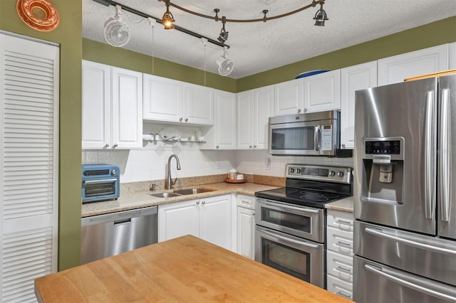 kitchen featuring sink, white cabinets, stainless steel appliances, and a textured ceiling