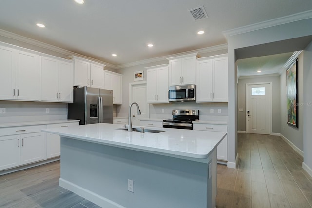 16819 Shell Bay Dr, Land O Lakes, FL 34638 - kitchen featuring appliances with stainless steel finishes, a sink, light countertops, white cabinetry, and a kitchen island with sink