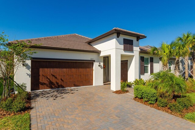 16819 Shell Bay Dr, Land O Lakes, FL 34638 - view of front of house featuring an attached garage, stucco siding, a tile roof, and decorative driveway
