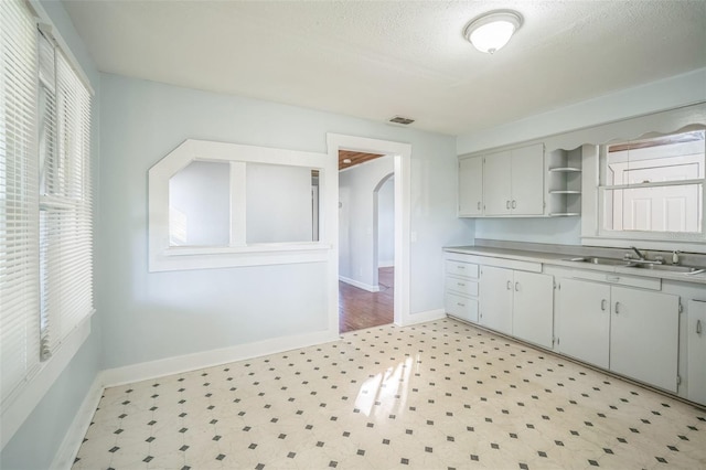 kitchen featuring sink, white cabinets, and a textured ceiling