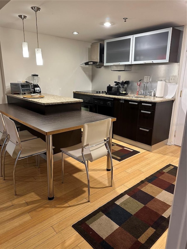 kitchen featuring pendant lighting, light wood-type flooring, and wall chimney exhaust hood