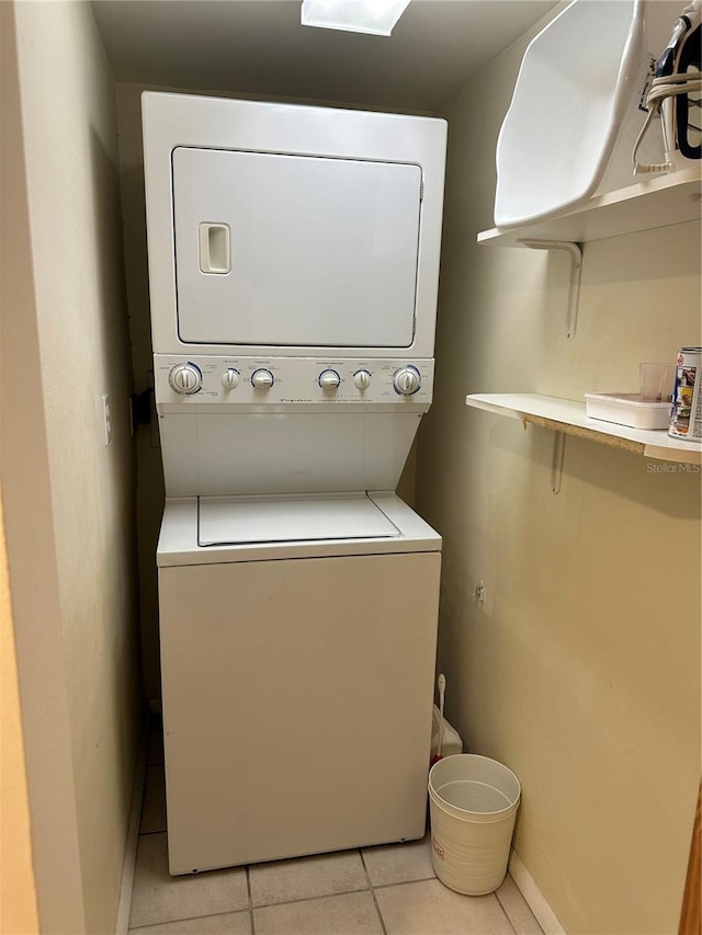 laundry room featuring stacked washer / drying machine and light tile patterned floors