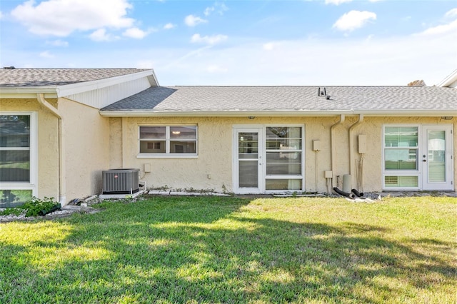 rear view of property featuring a lawn and central AC