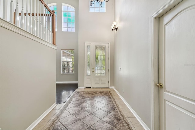 entryway with tile patterned flooring, a high ceiling, and a chandelier