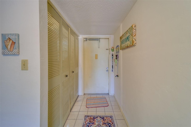 doorway to outside featuring light tile patterned flooring and a textured ceiling