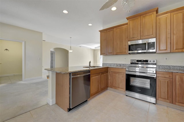 kitchen featuring light carpet, sink, light stone counters, kitchen peninsula, and stainless steel appliances