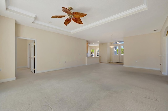 carpeted spare room featuring french doors, a tray ceiling, ceiling fan, and crown molding