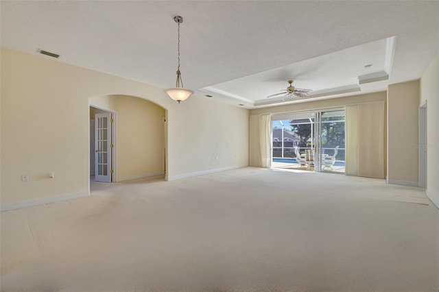 carpeted empty room with a raised ceiling and ceiling fan