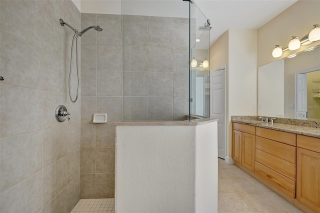 bathroom featuring tile patterned floors, vanity, and a tile shower