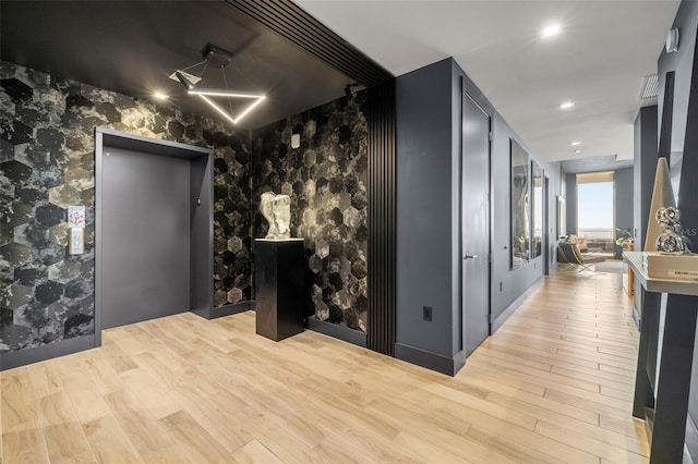 corridor featuring elevator and light hardwood / wood-style floors