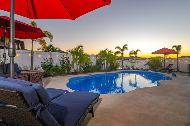 pool at dusk with a patio area