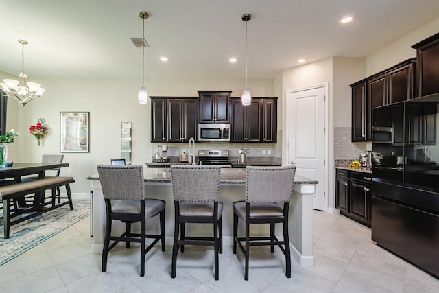 kitchen featuring a center island with sink, stainless steel appliances, and hanging light fixtures