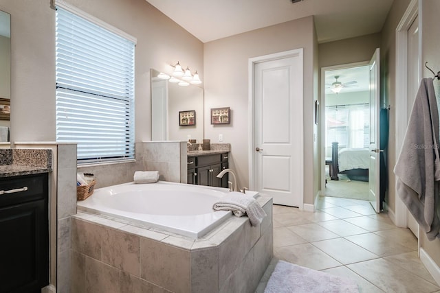 bathroom with tile patterned floors, tiled tub, ceiling fan, and vanity