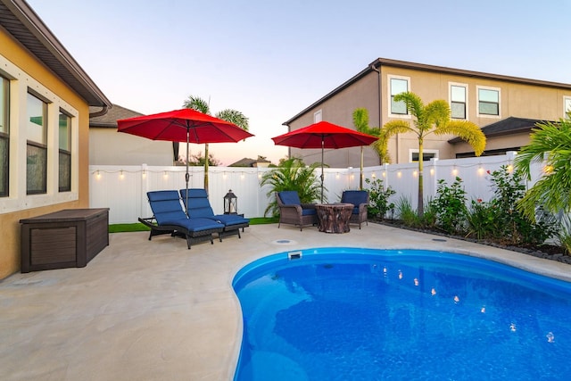 pool at dusk with a patio area