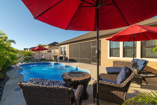 view of pool with pool water feature, a patio, and a sunroom