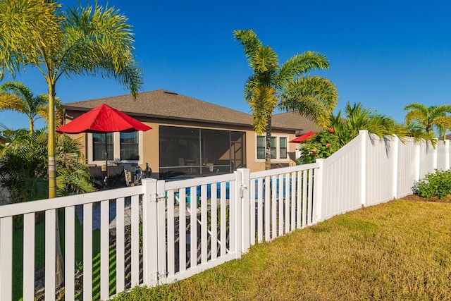 back of property featuring a sunroom and a lawn