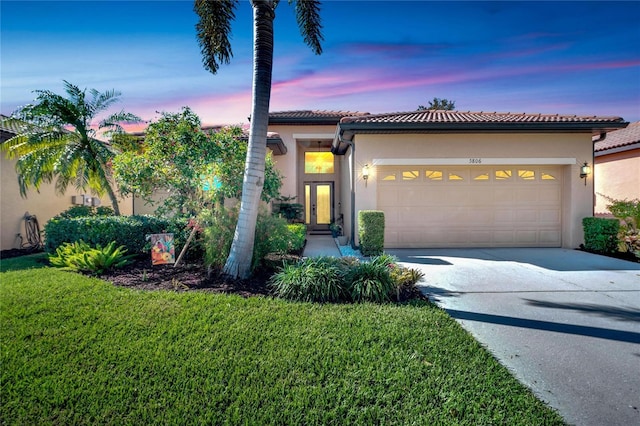 mediterranean / spanish house featuring a lawn and a garage