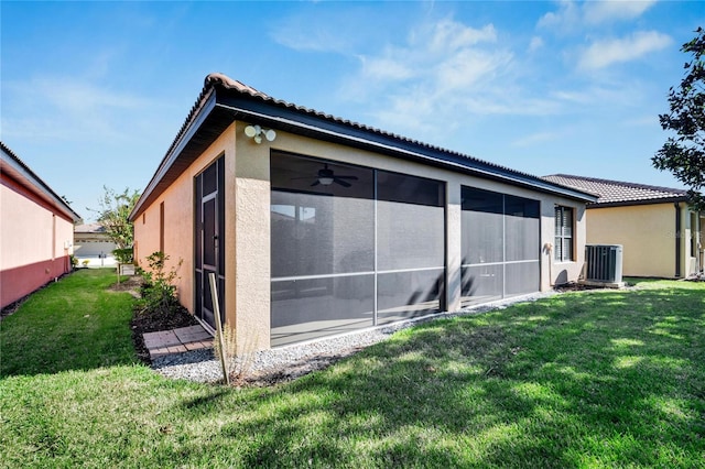 rear view of property with a sunroom, a lawn, and central AC