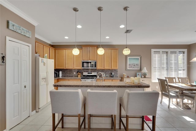 kitchen with decorative light fixtures, stainless steel appliances, a center island with sink, and ornamental molding